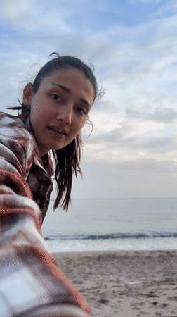 Woman plays fetch with poodle on Montenegro beach