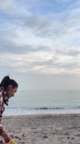 Woman plays fetch with poodle on Montenegro beach