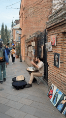 Street musician plays handpan on decorated Tbilisi sidewalk