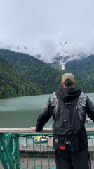 Man observes mountain lake from balcony in Abkhazia