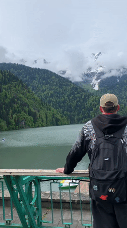Man observes mountain lake from balcony in Abkhazia