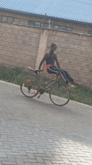 Young man coasts on bicycle along paved path in Nairobi