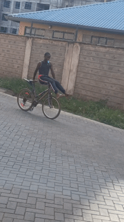 Young man coasts on bicycle along paved path in Nairobi