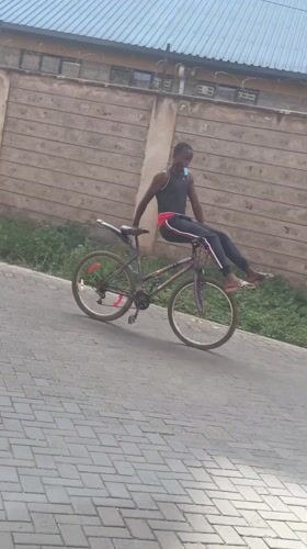 Young man coasts on bicycle along paved path in Nairobi