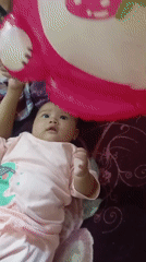Baby in pink dinosaur onesie plays on a blanket in Rejosari