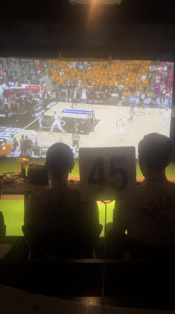 Two people watch basketball on big screen in NYC venue