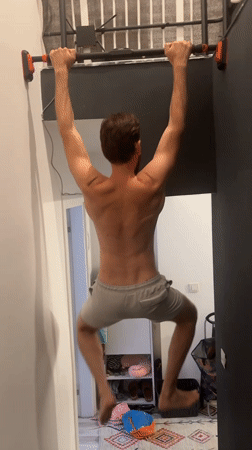 Man exercises with pull-ups in hallway, Fethiye Turkey