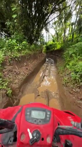 Red ATV navigates muddy terrain in Abiansemal, Indonesia