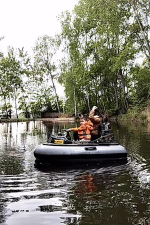 Child steers boat on Czech waterway with adult passenger