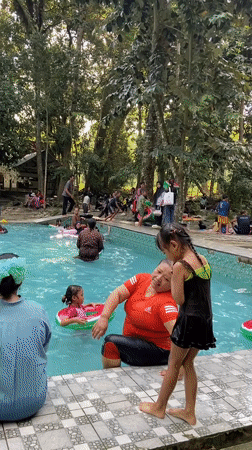 Crowded outdoor pool day at a green recreation spot in Java