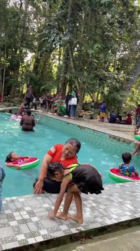 Crowded outdoor pool day at a green recreation spot in Java