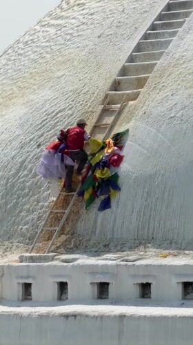 Man installs prayer flags near busy Buddhist temple in Kathmandu