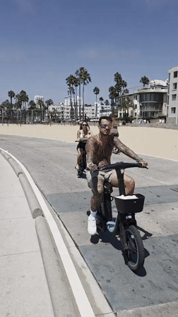 Cyclists and scooters cruise Santa Monica's sunny beachfront path