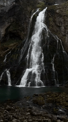 Multi-tiered waterfall tumbles down mossy Austrian cliff face