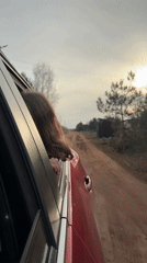 Girl leans from car window on rural roads near Chaikovsky