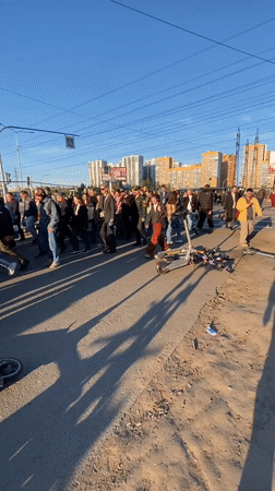 Large pedestrian group crosses street in Murino, Russia