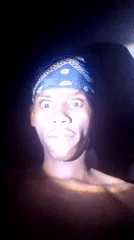 Young man in patterned bandana observed in darkened room