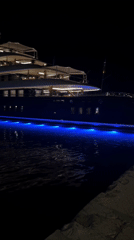 Yachts glowing with underwater lights at Ibiza marina after dark