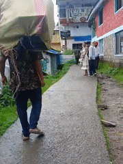 Heavy load carried through wet Dharamkot lanes at dawn