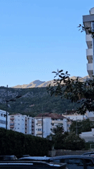 Urban afternoon scene with buildings, mountains captured by witnesses