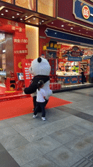 Child encounters panda performer on decorated street in Jinjiang