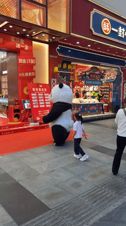 Child encounters panda performer on decorated street in Jinjiang