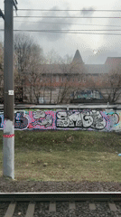 Train passenger views graffiti walls, spired building in Moscow