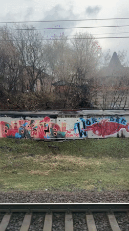 Train passenger views graffiti walls, spired building in Moscow