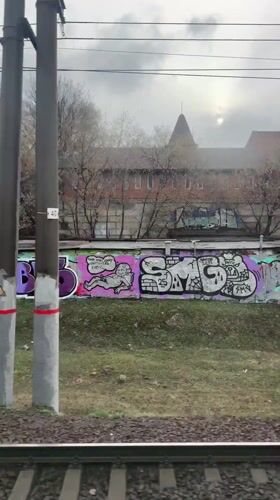 Train passenger views graffiti walls, spired building in Moscow