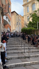 Skateboarder performs trick down stone steps before cheering crowd