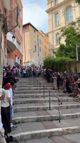 Skateboarder performs trick down stone steps before cheering crowd