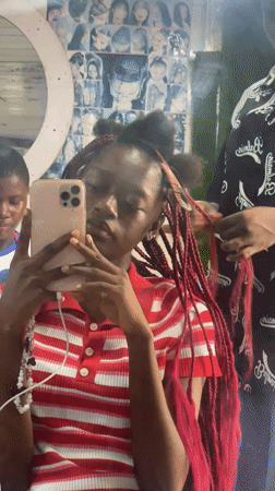 Young person takes selfie during hair appointment in Nigeria