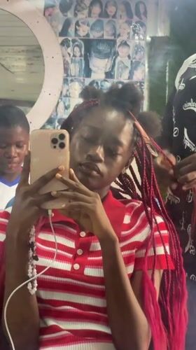Young person takes selfie during hair appointment in Nigeria