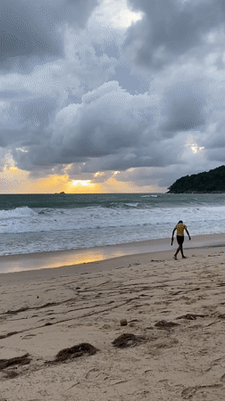 Dramatic sunset breaks through storm clouds at Thai beach