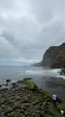 Man contemplates ocean from rocky shore in Santana