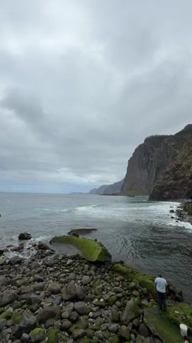 Man contemplates ocean from rocky shore in Santana