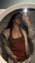 Woman takes mirror selfie in dimly lit establishment