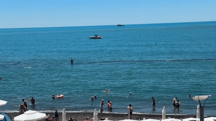 Sochi beach day: crowds, calm water, and coastal forest stairs