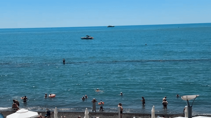 Sochi beach day: crowds, calm water, and coastal forest stairs