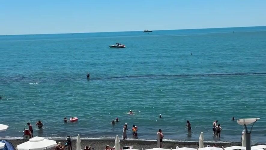 Sochi beach day: crowds, calm water, and coastal forest stairs