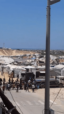 Crowds gather at a water truck in Khan Yunis camp