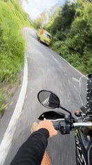 Motorcycle rider travels scenic Kintamani road, encounters yellow truck
