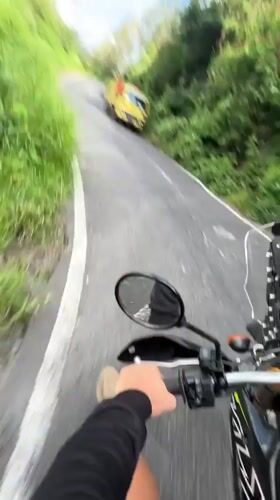 Motorcycle rider travels scenic Kintamani road, encounters yellow truck