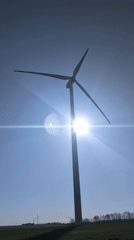 Wind turbine operates against bright morning sky in Bulgaria