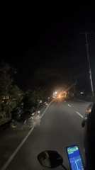 Motorcycle rider navigates dark road in Mengwi, Indonesia