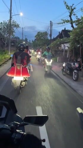 Scooter convoy recorded on Ubud road at dusk