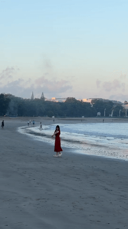 Kuta Beach at golden hour, people, shoreline, and Bali landmarks