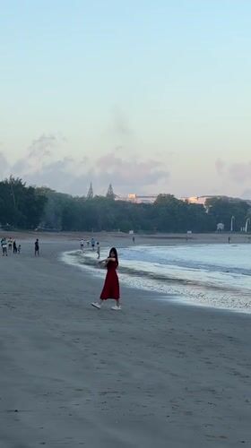 Kuta Beach at golden hour, people, shoreline, and Bali landmarks