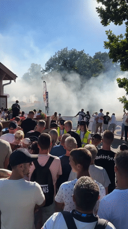 Crowd watches smoky vehicle performance at outdoor event
