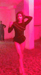 Woman dances alone in dimly lit room with colored lighting
